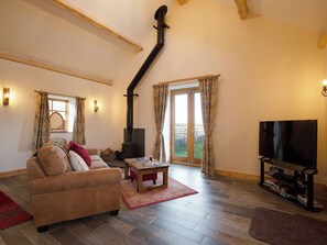 A living room with a sofa, a television, a fireplace, and a large window.