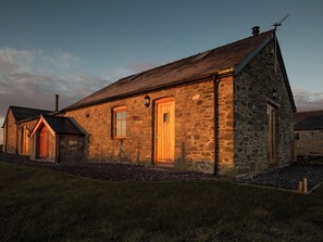 A stone building with a sloped roof, a wooden door, and a small window.