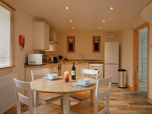 A kitchen with a dining table, chairs, a candle, and a bottle of wine.