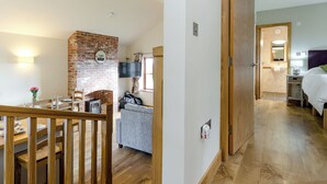 A hotel room with a wooden staircase, a brick fireplace, a flat-screen TV, and a bed with a headboard. - Tawny Cottage - UKC2580 (Yoxall, near Lichfield)