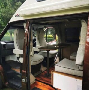 Relax and socialize in this well-maintained RV's seating area, featuring a central table and two comfortable chairs.