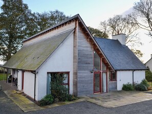 A small, single-story building with a sloped roof, a front door, and a visible window.