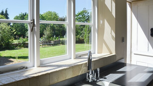A kitchen with a large window, a sink, and a view of a garden.