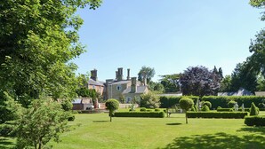A well-maintained lawn, a wooden bench, and a stone building with multiple chimneys.