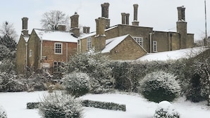 A historic building with multiple chimneys, brick walls, and snow-covered surroundings.