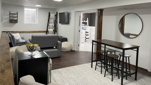 Ein modernes Wohnzimmer mit einer Couch, einem Couchtisch und einem Essbereich mit Hockern.