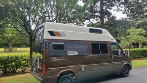 A brown camper van parked on a road with a website address visible on the side. - Camper 8 “Bertha” (Leinster)