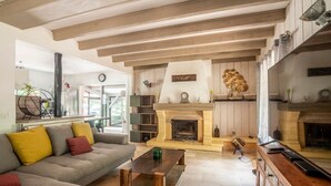 Ein Wohnzimmer mit Kamin, Holzbalken, einer Couch und einem Couchtisch.