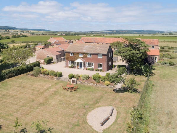 Une grande maison en briques, dotée de nombreuses pièces, d’une pelouse bien entretenue et d’une allée gravillonnée.