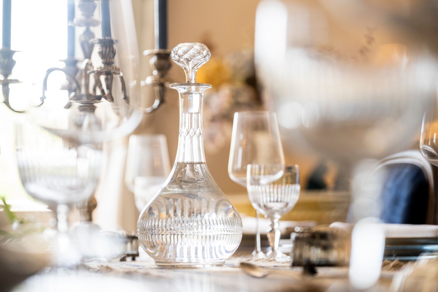 A dining table with a crystal decanter and wine glasses.