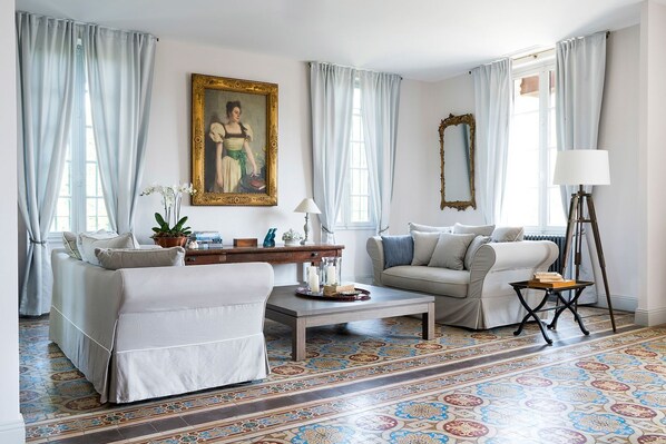 A living room with a sofa, a coffee table, a lamp, a floor lamp, a painting, and a mirror.