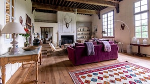 A rustic living room with a fireplace, wooden beams, and a purple sofa. - Manoir Gascon - Five Bedroom Villa, Sleeps 12 (Estang)