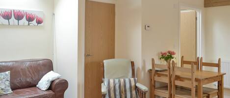 Una habitación con una mesa de comedor de madera, una silla acolchada, un sofá de cuero y una puerta de madera.