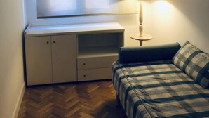 Une petite pièce agréable, dotée d’un lit, d’un bureau avec une lampe et d’une fenêtre avec des rideaux.