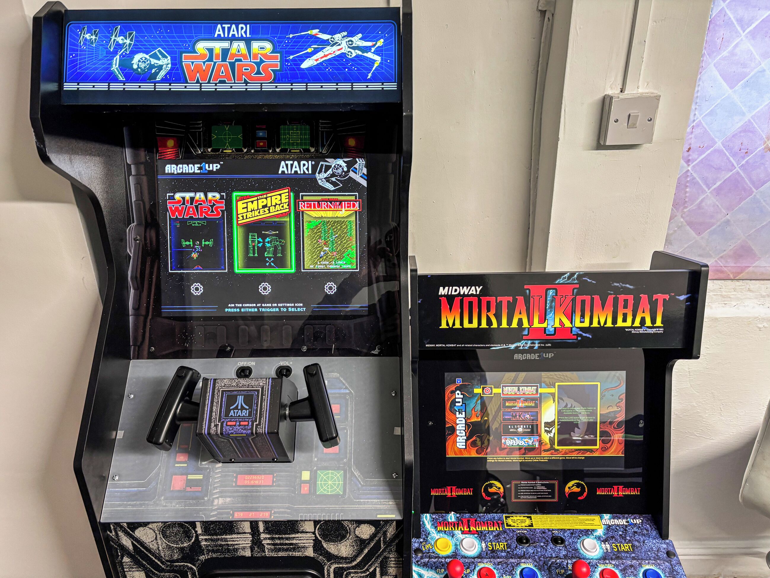 Two arcade machines, one for Star Wars and one for Mortal Kombat, with joystick controls and game selection screens.