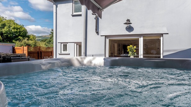 Un jacuzzi situé devant un bâtiment, avec une terrasse couverte.