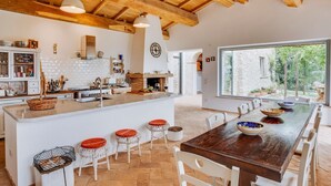 A spacious kitchen with a large island, white bar stools, and a dining area with a wooden table and chairs. - Villa Todari - Three Bedroom Villa, Sleeps 10 (Torricella in Sabina)
