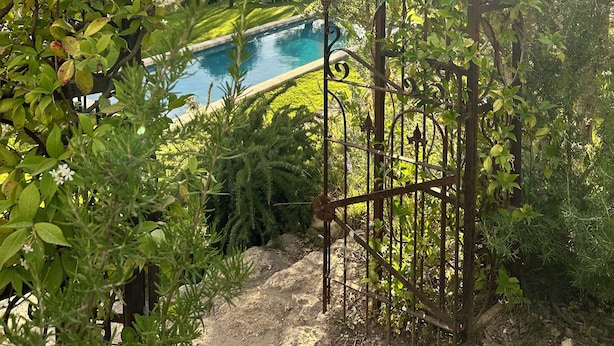 A garden with a pool, surrounded by lush greenery and a metal archway. - Bastide sleeps 9, large secure swimming pool, not overlooked in Aix en Provence (Aix-en-Provence)