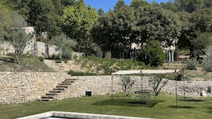 A swimming pool with a stone border, surrounded by a grassy lawn and a stone wall. - Bastide sleeps 9, large secure swimming pool, not overlooked in Aix en Provence (Aix-en-Provence)
