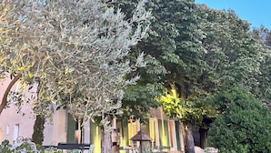A courtyard with a pergola, seating area, and a building with large windows. - Bastide sleeps 9, large secure swimming pool, not overlooked in Aix en Provence (Aix-en-Provence)