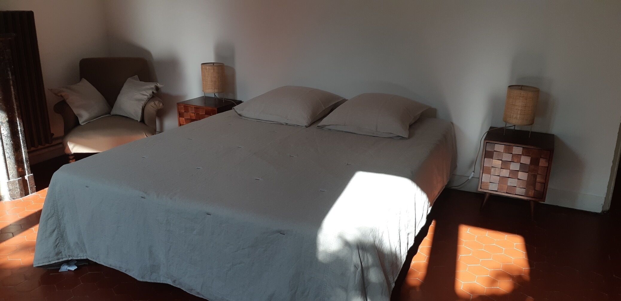 A bedroom with a large bed, two bedside tables, a chair, and a lamp.