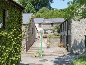Un edificio in pietra dal design tradizionale, un cortile lastricato e un lampione verde.