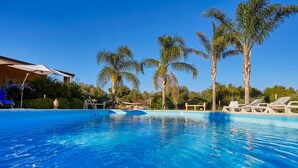 Une piscine d’un bleu éclatant, avec des chaises longues et des palmiers.