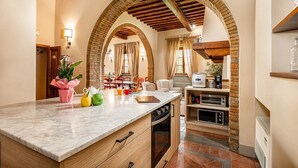 A kitchen with a marble countertop, wooden cabinets, and a brick archway.