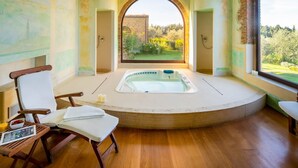 A spa room with a hot tub, wooden chairs, and a view of a garden.