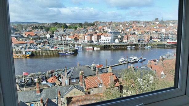 A view of a harbor with boats, buildings, and a church spire in the distance.