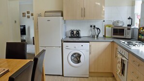A compact kitchen with a washing machine, a microwave, and a gas stove.