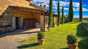 A stone building with a covered outdoor seating area, a stone staircase, and a well-maintained lawn with two potted topiaries. - Villa Tirelli - Five Bedroom Villa, Sleeps 10 (San Casciano dei Bagni)