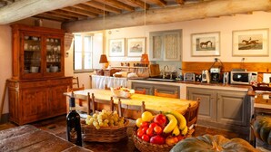A rustic kitchen with wooden beams, a wooden cabinet, a dining table with fruit, and kitchen appliances. - Villa Tirelli - Five Bedroom Villa, Sleeps 10 (San Casciano dei Bagni)