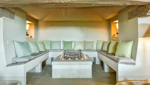 Un coin salon accueillant avec une cheminée en pierre, des bancs rembourrés et un éclairage d’ambiance.