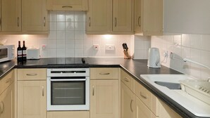 A kitchen with light wood cabinets, a white oven, a microwave, and a toaster.