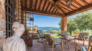 Un patio con mobiliario de mimbre, una estatua y vistas al campo.