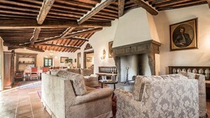 Un salón comedor amplio con techo de madera alta, chimenea y asientos cómodos.