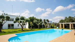 Une piscine dotée d’une terrasse en bois, entourée d’une pelouse bien entretenue et d’arbres.