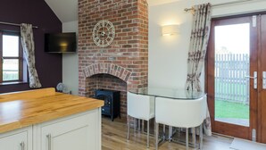 Een moderne keuken met een bakstenen open haard, witte kasten en een houten aanrecht.