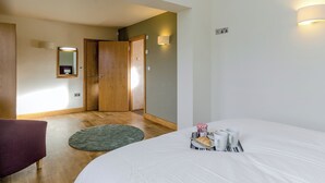 Hotelkamer met een bed, een stoel, een klein tafeltje met een croissant, een kopje en een potje jam.