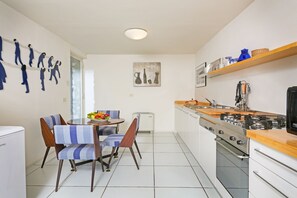 A compact kitchen with a dining area, featuring a stove, oven, and a refrigerator.