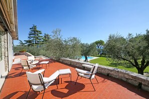 Una terrazza esterna con poltrone da relax bianche e un muro in pietra.