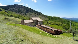 A stone house with a sloped roof, surrounded by lush green hills and a clear blue sky. - Villa Sasseta - Eight Bedroom Villa, Sleeps 16 (Zignago)