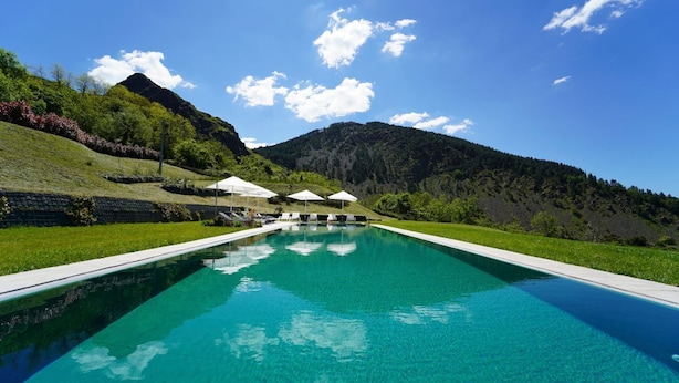 A rectangular swimming pool with clear blue water, surrounded by a grassy area with lounge chairs and umbrellas. - Villa Sasseta - Eight Bedroom Villa, Sleeps 16 (Zignago)