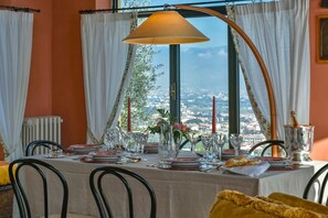 A dining table set for two with a view of a cityscape through a large window.