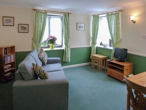 A living room with a sofa, a television, a small table, and a bookshelf.