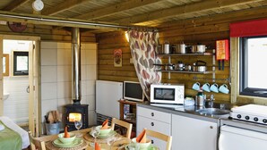 A cozy cabin interior with a dining area, kitchen, and a wood-burning stove. - Kestrel Cabin - UK1246 (Brocklebank, near Caldbeck and Uldale)