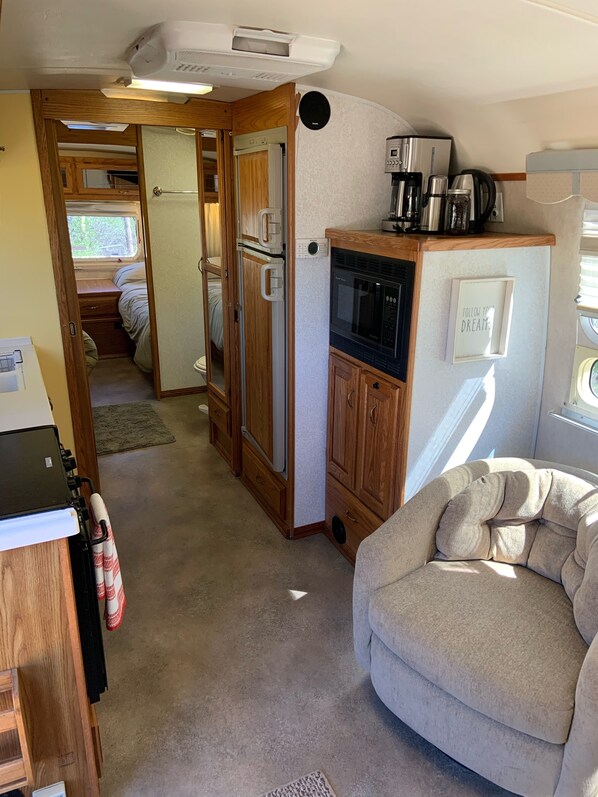 Interior compacto de autocaravana con kitchenette, cama y zona de estar.