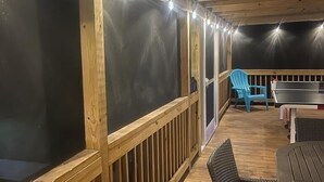 Une terrasse extérieure avec des rampes en bois, une table, des chaises et des guirlandes lumineuses.
