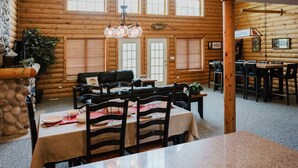 A cozy log cabin interior with a dining area, wooden walls, and a stone accent wall. - Jacuzzis & Family Kitchen & Entertainment Area (North Utica)